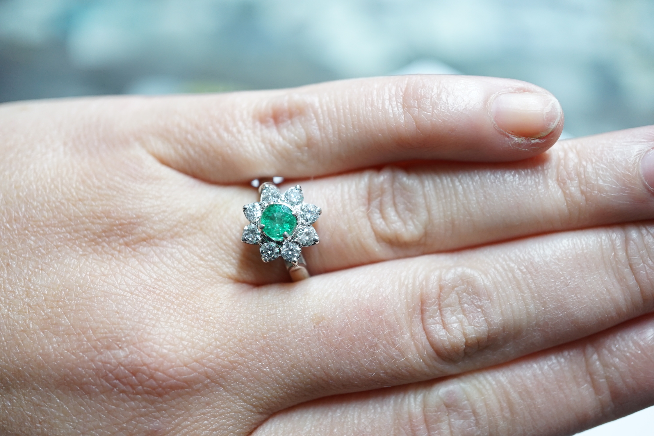 A modern 18k white metal, emerald and diamond set flower head cluster ring, size N, gross weight 4.5 grams.